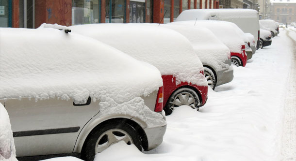snow piled up on parked cars with gas prices rising